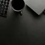 Laptop with open book on desk symbolizing online reading and digital education.